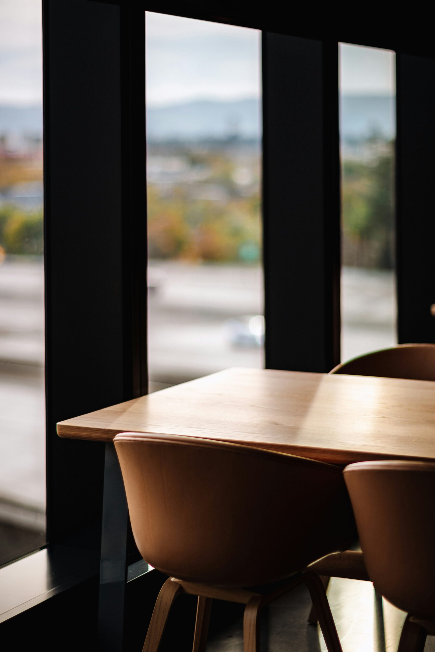 Bruna höga stolar i läder vid bord. Utsikt över berg med höstfärger.