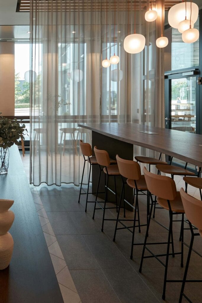 Vision of the first floor office. Meeting room with tables, lamps, high ceilings and textiles